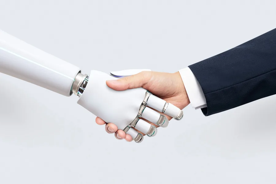 Człowiek i robot podający sobie dłonie jako symbol współpracy z AI
